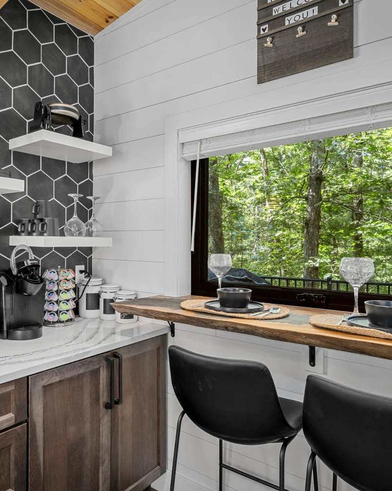 Whispering Pines - Twilight - Full Kitchen with View Large set of windows next to a fireplace that show a wide view of trees and nature in the Whispering Pines cabin