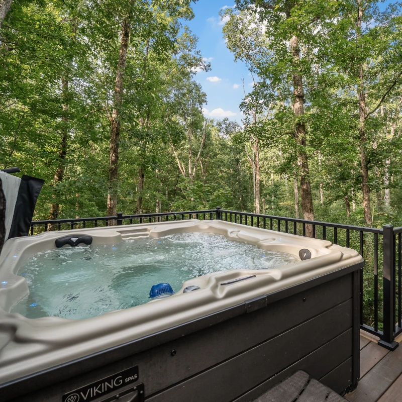 A large hot tub sits overlooking a private lake at Whispering Pines cabin.