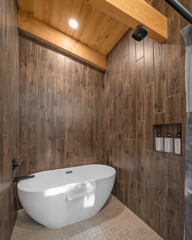 Large set of windows next to a fireplace that show a wide view of trees and nature in the Whispering Pines cabin